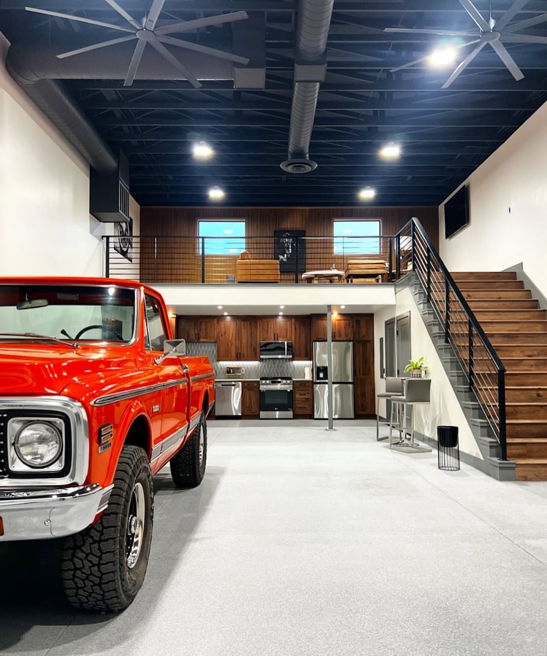 Red vintage truck parked in a modern garage with a kitchen and a loft above.