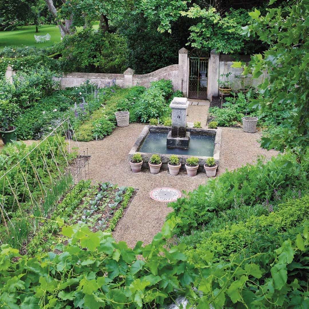 10 Potager Garden Ideas for Every Yard Size and Budget 2 A lush potager garden with gravel paths, vegetable beds, and a central stone water fountain.