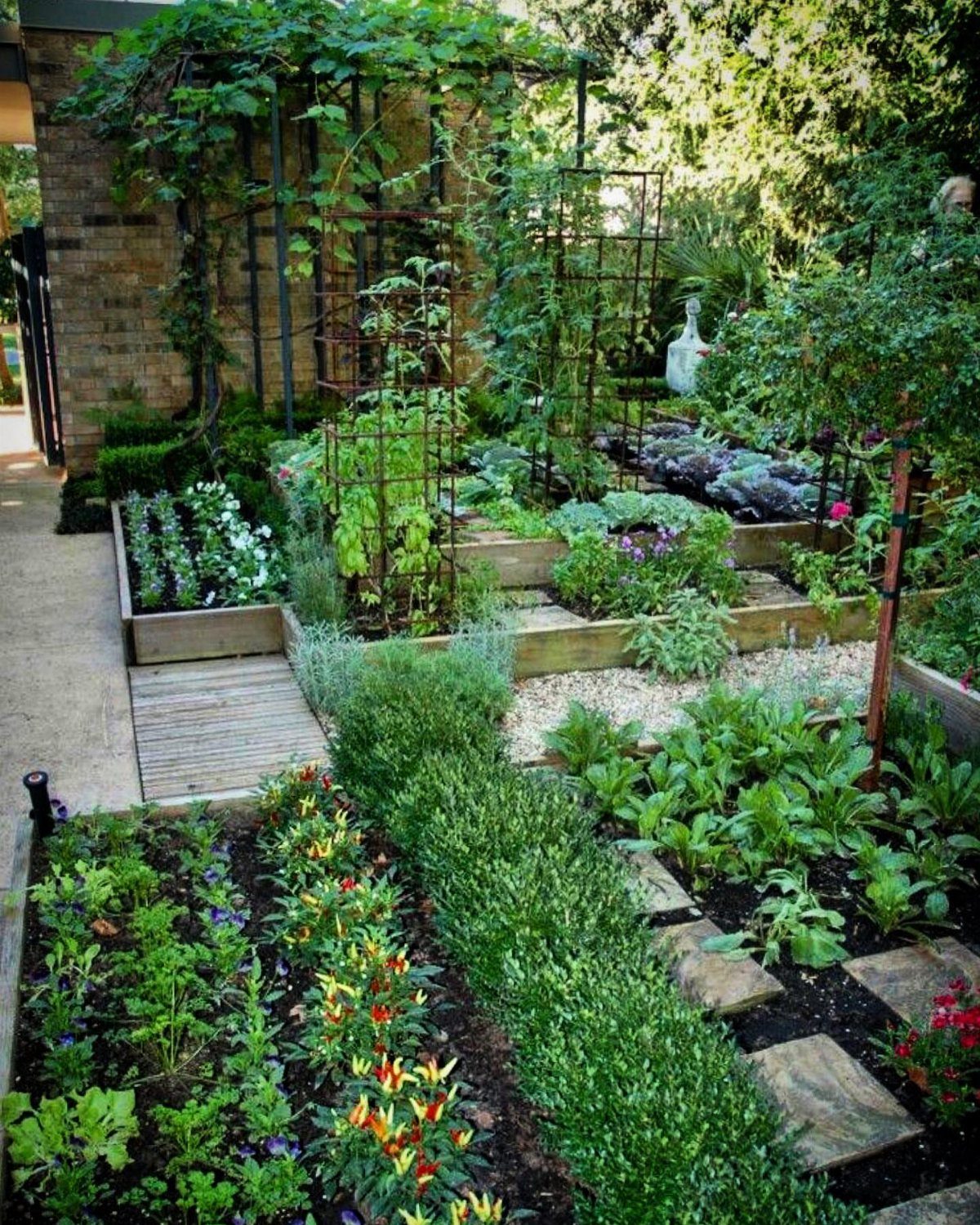 10 Potager Garden Ideas for Every Yard Size and Budget 6 A lush potager garden with wooden raised beds, colorful flowers, and various edible plants and herbs.