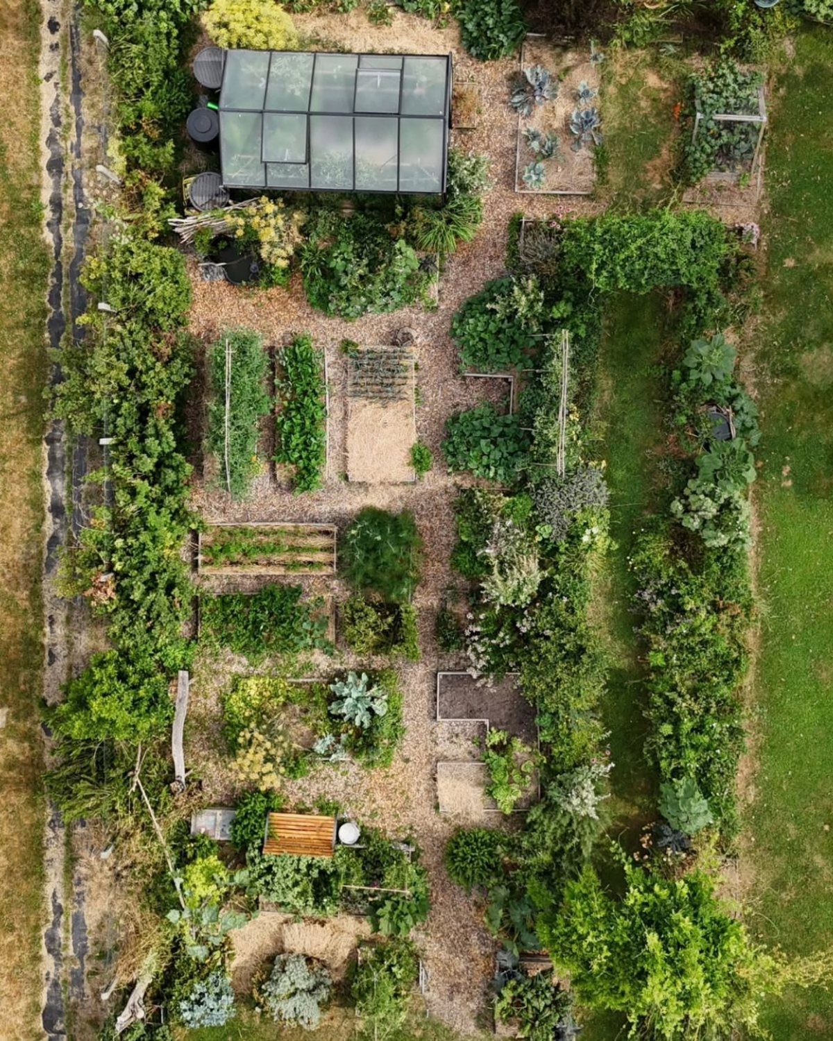 10 Potager Garden Ideas for Every Yard Size and Budget 9 Aerial view of a structured potager garden with vegetable beds, a greenhouse, and winding paths.