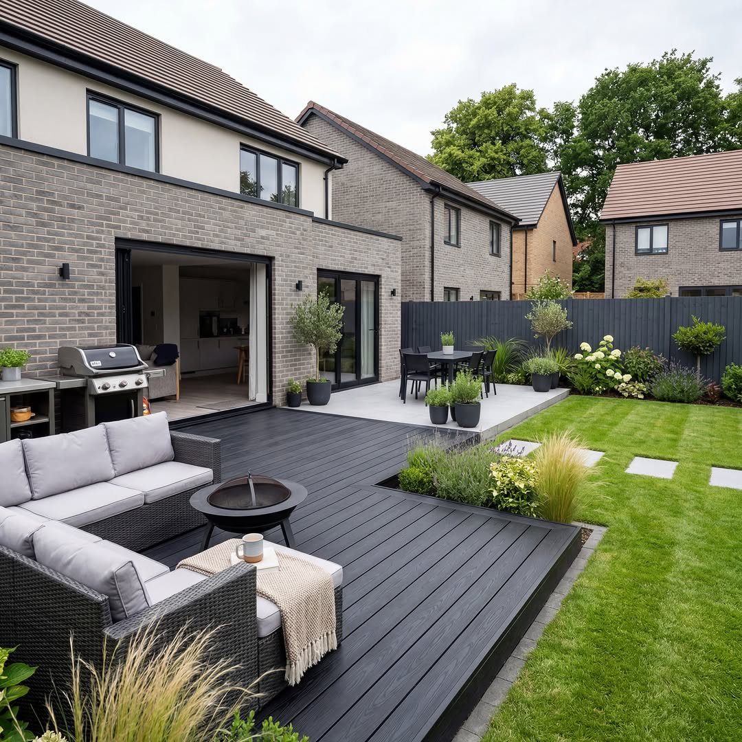 Dark grey composite decking surrounds a modern outdoor living space with lounge furniture and a lawn.