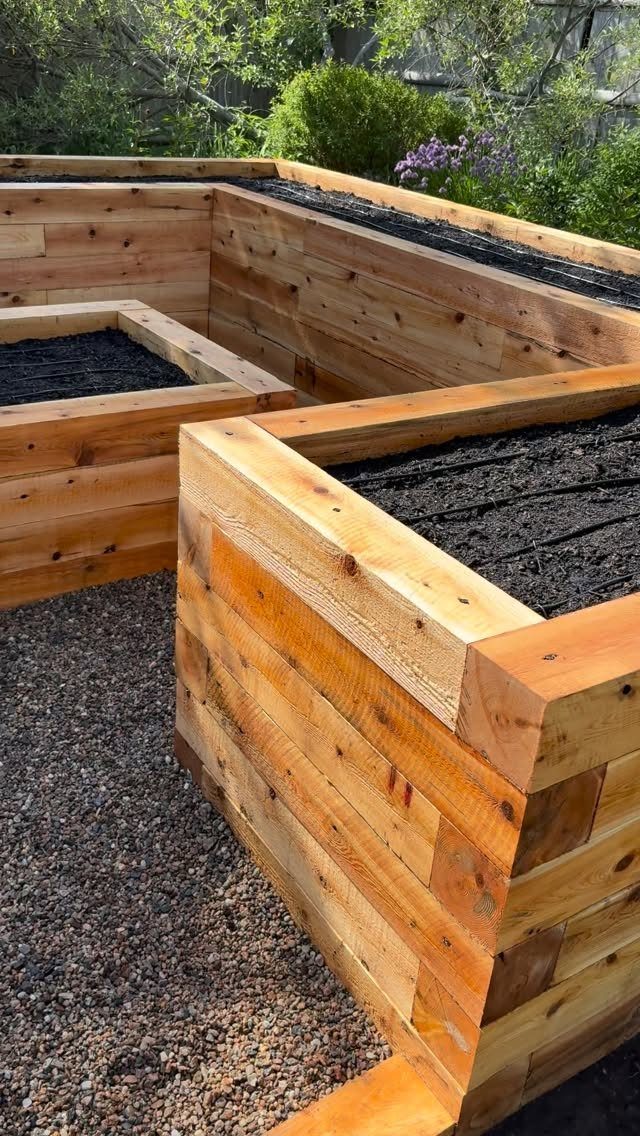 Simple Garden Layout Ideas for 2026: 12 Plans to Try 1 Wooden raised garden beds filled with dark soil sitting on a gravel path outdoors.