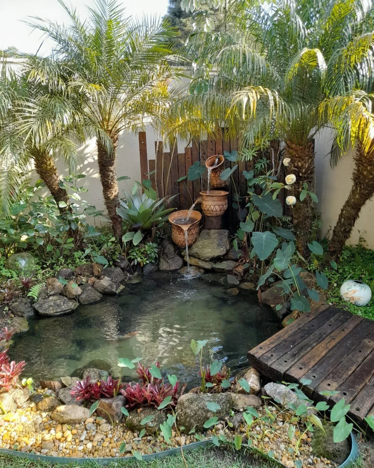 Simple Garden Layout Ideas for 2026: 12 Plans to Try 5 A small tropical garden pond with terracotta pot water features and palm trees.