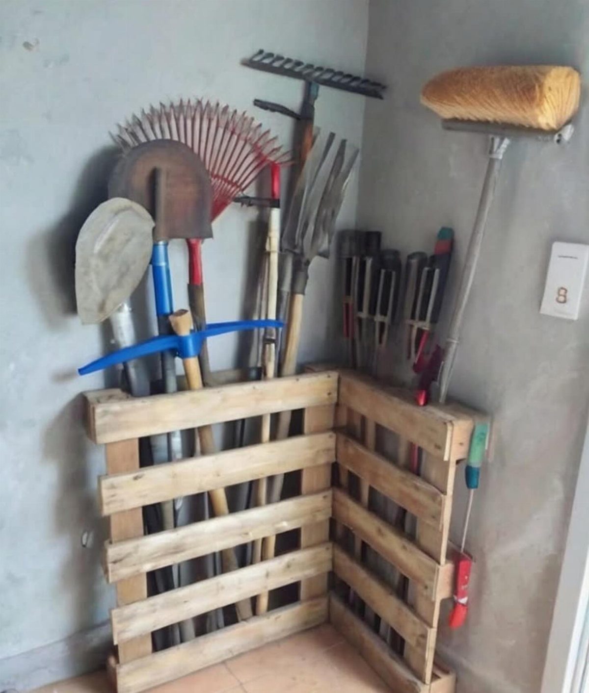 13 Unique Garden Ideas for Planters, Privacy Screens and Pallet Projects 4 Wooden pallet tool holder standing in a corner holding various garden rakes and shovels.
