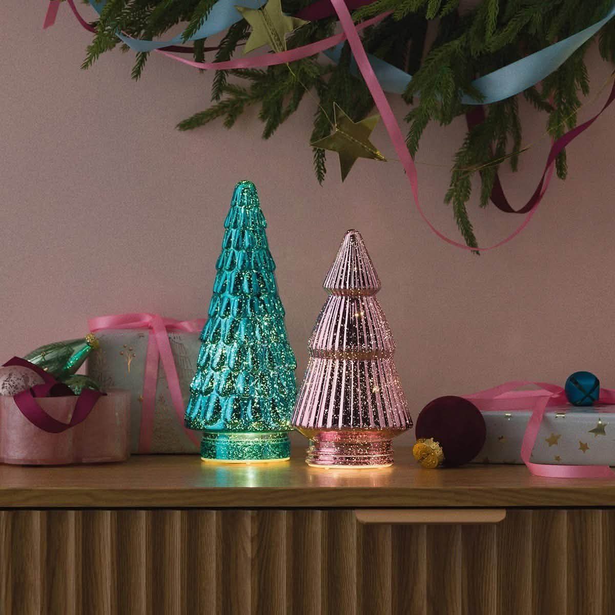 12 Xmas Table Decorations for Pine Cones, Mercury Glass, and Blue-Gold Palettes 7 Two illuminated mercury glass Christmas trees in teal and pink on a wooden sideboard.