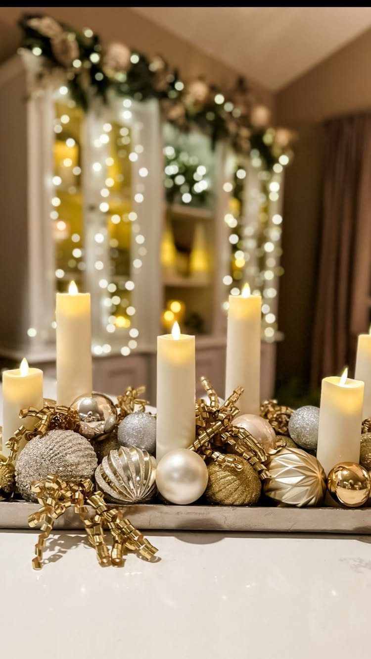 12 Xmas Table Decorations for Pine Cones, Mercury Glass, and Blue-Gold Palettes 11 White pillar candles and metallic ornaments arranged on a tray with festive lights in the background.