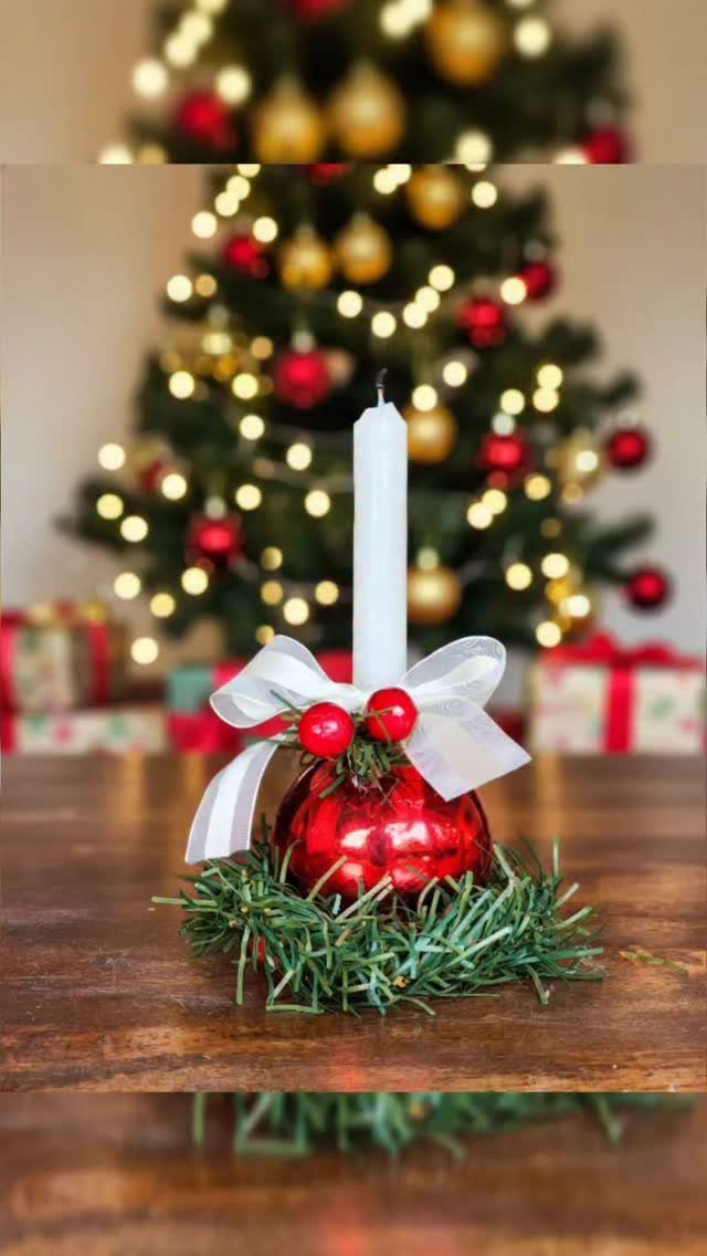 12 Xmas Table Decorations for Pine Cones, Mercury Glass, and Blue-Gold Palettes 6 A white taper candle decorated with a red ornament, white bow, and greenery on a wooden table.