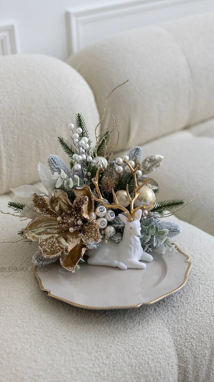 12 Xmas Table Decorations for Pine Cones, Mercury Glass, and Blue-Gold Palettes 8 A white reindeer figurine surrounded by gold flowers and frosted greenery on a plate.